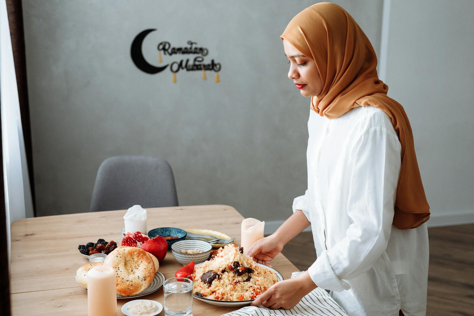 a woman wearing hijab serving the food on the table